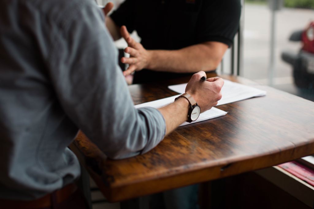 hands visible above a wooden table as two people are engaged in a discussion